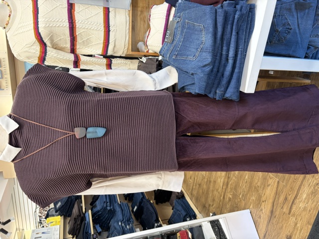 Ribbed plum sweater vest over a white shirt with plum corduroy flares